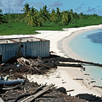 **

A desolate island scene in the Marshall Islands, illustrating the dual threats of nuclear legacy and rising sea levels. In the foreground, a dilapidated, cracked structure labeled "DOM" (nuclear waste storage) sits partially submerged in encroaching ocean water. Deformed vegetation struggles to grow amidst contaminated soil. In the background, a faded photograph depicts smiling islanders from the 1950s, juxtaposed with the stark reality of the present day. The overall tone is melancholic and cautionary, highlighting the environmental and cultural devastation.

**